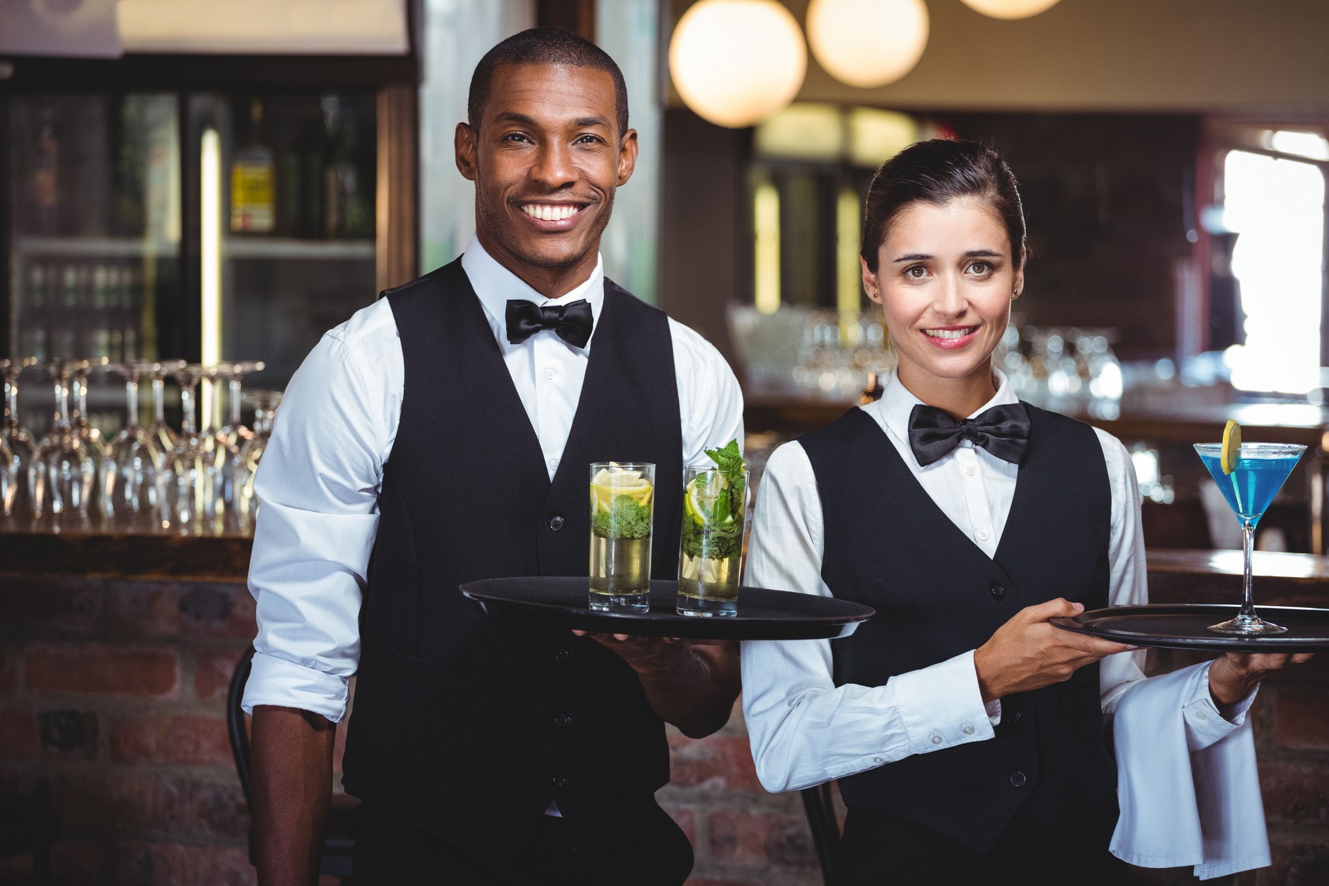 Serveur et serveuse tenant un plateau avec verre de cocktail